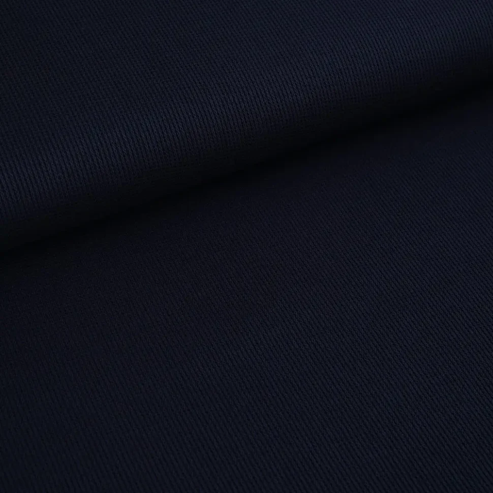 Close-up of dark navy fabric with a diagonal weave and a fold running across the material.