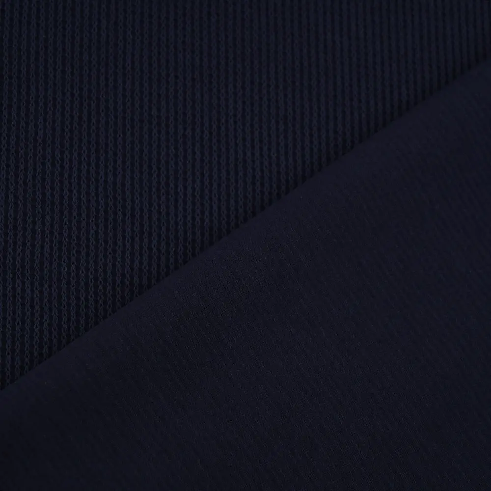 Close-up of dark navy fabric showing a ribbed knit texture on one side and a smooth weave along a diagonal seam nearby.