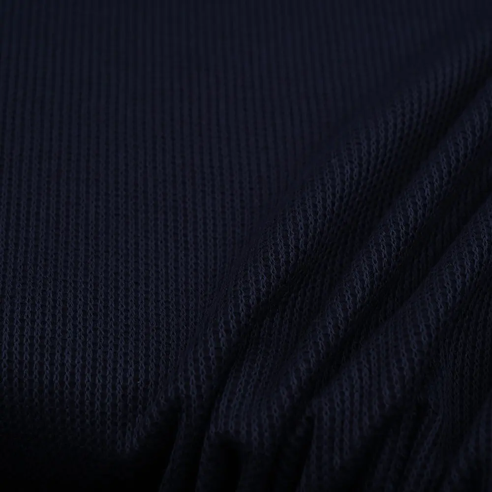 Close-up of dark navy knitted fabric with a ribbed texture and folded areas in the corner.