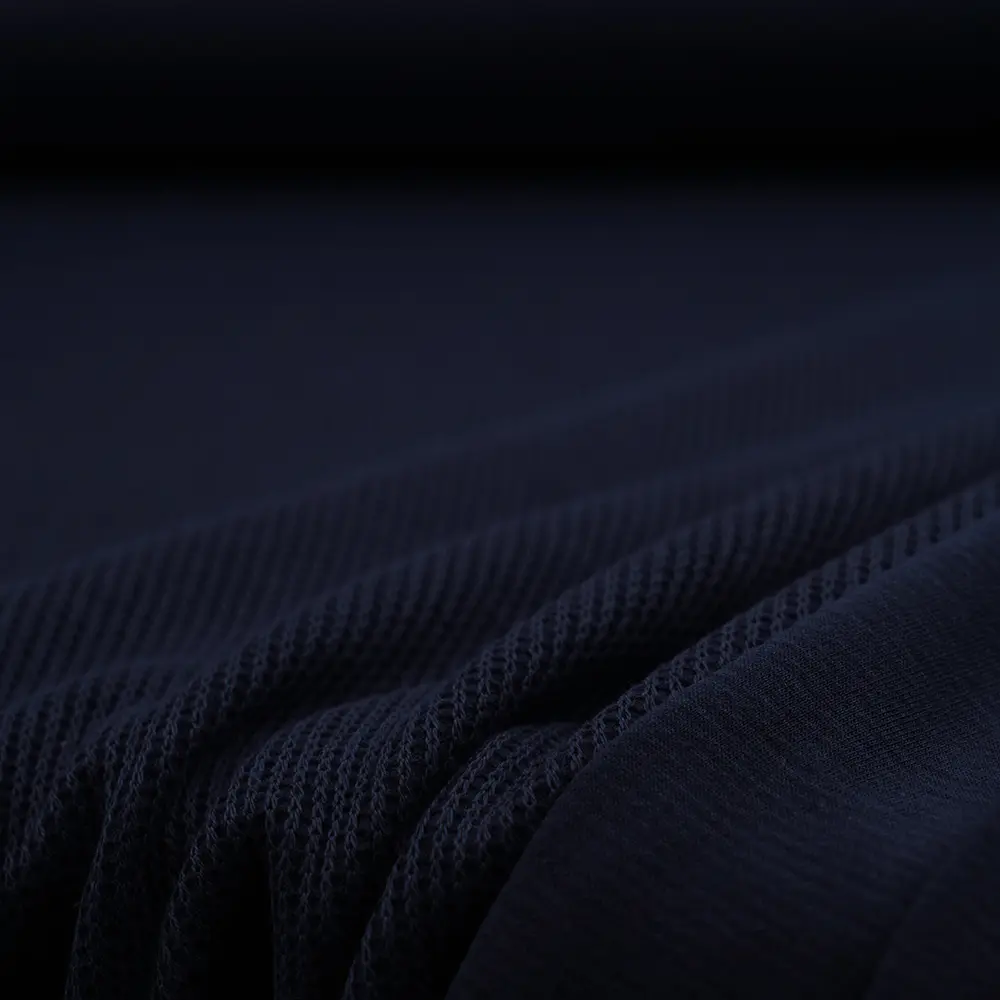 Close-up of dark navy fabric with a fine knit texture and soft folds