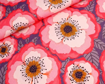 Close-up of pink and red poppy flowers with orange centers and black stamens on a purple background fabric.